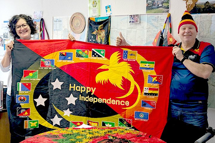 Geschäftsführer Martin Habelt und Freiwilligenreferentin Susann Küster-Karugia halten eine Flagge mit der Botschaft "Happy Independence" (Alles Gute zur Unabhängigkeit) und gratulieren damit zum Unabhängigkeitstag.