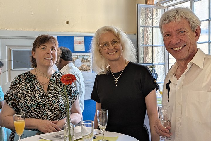 Direktorin Annette Kalettka, Oberkirchenrätin Petra Schwermann und Pfarrer in Ruhe Matthias Simon an einem Stehtisch beim Empfang. Alle lachen in die Kamera.